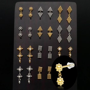 May include: A display of gold and silver earrings with various designs, including geometric shapes and floral motifs. The earrings are arranged on a black background.