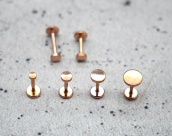 Puede incluir: Un conjunto de seis piezas de joyería corporal de color dorado. Las piezas son de diferentes tamaños y formas, incluyendo redondas y cuadradas.