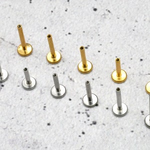 May include: A collection of 12 gold and silver body jewellery pieces. The jewellery is in the shape of a stud with a small ball on the end. The studs are arranged in two rows, with the gold studs on the top row and the silver studs on the bottom row.