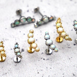 Könnte beinhalten: Ein Set aus sechs Opal-Körper-Schmuckstücken in Silber und Gold. Der Schmuck hat ein Halbmond-Design mit Opal-Steinen.