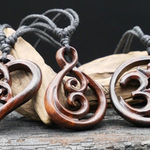 May include: Three wooden necklaces with different pendants. The first pendant is a heart with a Celtic knot design. The second pendant is a stylised infinity symbol. The third pendant is a circle with the Om symbol carved into it.