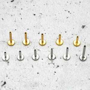 May include: A set of 12 body jewellery pieces, including 6 gold and 6 silver labret studs. The studs are arranged in two rows on a white surface.