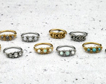 May include: A set of ten nose rings with different designs and gemstones. The rings are made of gold and silver and feature various gemstones, including turquoise, opal, and pearls.
