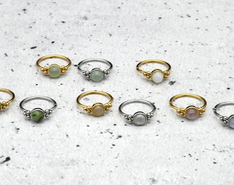 May include: Set of ten gold and silver rings with oval-shaped gemstones. The rings have a beaded design around the gemstone.