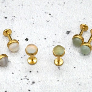 Può includere: Sei pezzi di gioielleria per il corpo dorati con pietre di diversi colori. Le pietre sono rotonde e hanno una finitura liscia e lucida. Due delle pietre sono di colore verde chiaro, due sono di colore bianco e due sono di colore giallo chiaro.