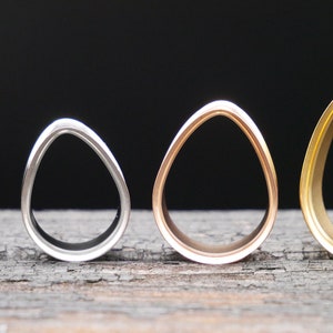 May include: Four different sized, oval-shaped, metal ear gauges. The gauges are black, silver, rose gold, and gold.
