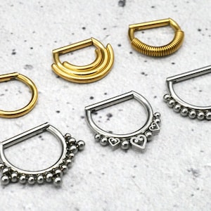 Könnte beinhalten: Sechs verschiedene Stile von Septumringen in Gold und Silber. Die Ringe sind alle aus Metall und haben unterschiedliche Designs, darunter eine Spirale, ein Doppelring und eine Reihe von Perlen.