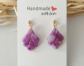 May include: A pair of handmade purple earrings with a leaf-like design. The earrings are attached to gold-colored posts and feature a marbled effect with gold flecks. The card behind the earrings reads "Handmade with love."