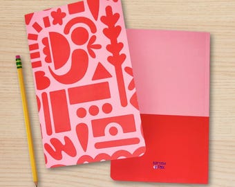 May include: Two notebooks with pink and red covers and a yellow pencil. One notebook has a pink cover with a red abstract design. The other notebook is pink and red. The pencil is sharpened.