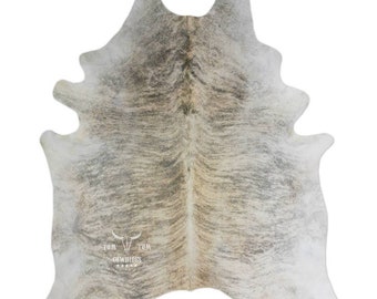 May include: A gray and white cowhide rug with a brown stripe down the center. The rug has a natural, rustic look and is perfect for adding a touch of Western style to any room.