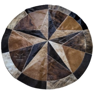 May include: A round cowhide rug with a starburst pattern in shades of brown, black, and white. The rug is made of multiple pieces of cowhide sewn together. The center of the rug features the text "TOM COWHIDES" with a stylized bull's head.