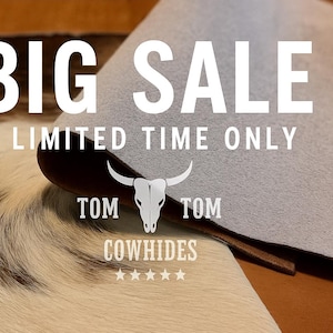May include: Image featuring a cowhide with the text "BIG SALE - LIMITED TIME ONLY." The Tom Tom Cowhides logo, a skull with horns, is displayed. The cowhide has a mix of brown, white, and black fur.