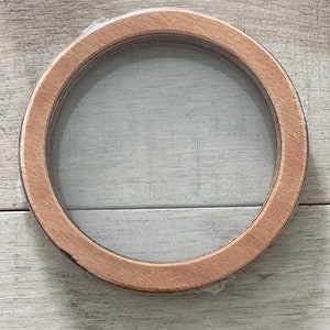 Puede incluir: Un marco redondo de madera con un inserto de vidrio transparente. El marco est&aacute; hecho de madera natural y tiene un aspecto r&uacute;stico.