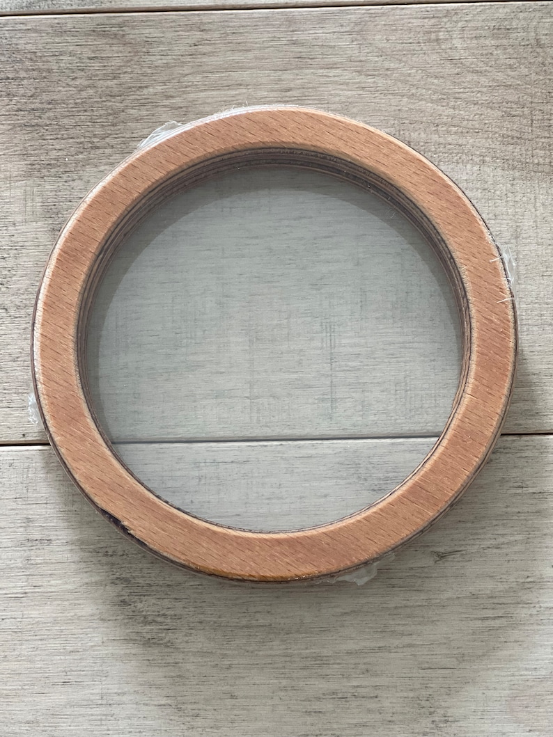 Puede incluir: Un marco redondo de madera con un inserto de vidrio transparente. El marco est&aacute; hecho de madera natural y tiene un aspecto r&uacute;stico.
