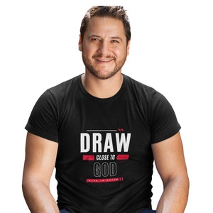 May include: A black t-shirt with white text that reads "DRAW CLOSE TO GOD LIVE IN FAITH". The text is in a bold, sans-serif font. The words "CLOSE TO" are in red.
