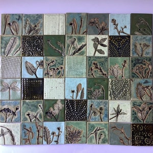 May include: A mosaic tile sheet featuring a green and blue colour scheme. The tiles display a range of botanical designs, including leaves, flowers, and stems. The tiles are arranged in a grid pattern.