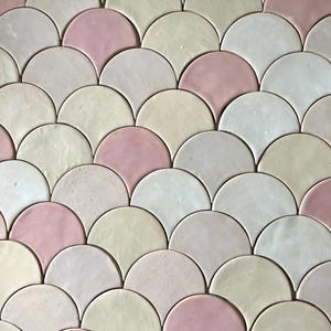 Puede incluir: Primer plano de una pared enlosada con un patrón de semicírculos superpuestos en tonos rosa, crema y gris.