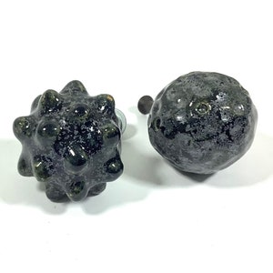 May include: Two black ceramic knobs with a speckled finish. One knob is round and the other is a spiky sphere.