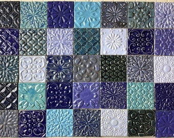 May include: A collection of 48 square ceramic tiles in various shades of blue, teal, and white. Each tile features a unique embossed floral or geometric pattern. The tiles are arranged in a grid, showcasing a variety of textures and designs.
