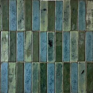 May include: A collection of rectangular ceramic tiles in shades of green and blue. The tiles are arranged in vertical rows, creating a textured surface. The colour variations and speckled patterns give the tiles a rustic appearance.