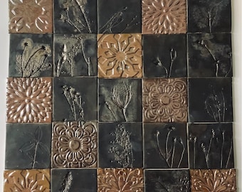 May include: A black and brown tile mosaic with a repeating pattern of floral designs and dried plant sprigs. The tiles are arranged in a grid pattern.