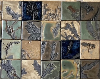 May include: A collection of 36 square ceramic tiles with a variety of botanical designs in shades of brown, green, and blue. The tiles are arranged in a grid pattern.
