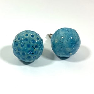 Peut inclure: Deux boutons de cabinet en céramique bleue avec une finition mouchetée. Un bouton a une surface texturée avec de petits points en relief.