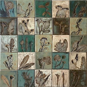 Puede incluir: Un conjunto de 25 azulejos de cerámica con un tema botánico. Cada azulejo presenta un diseño diferente de hoja o flor prensada en tonos de verde, marrón y blanco.