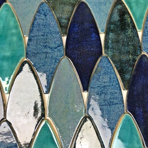 May include: A close-up of a mosaic tile sheet featuring a variety of blue, green, and white glazed ceramic tiles in a fish scale pattern.