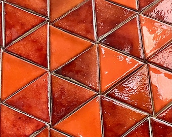 May include: A close-up of a wall covered in orange and brown triangular tiles. The tiles are arranged in a geometric pattern, creating a visually appealing and textured surface.