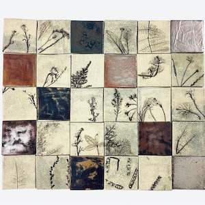 Könnte beinhalten: Eine Wandmosaik aus 25 quadratischen Fliesen. Jede Fliese zeigt einen anderen Schwarz-Weiß-Pflanzenabdruck auf cremefarbenem Hintergrund. Die Fliesen sind in einem Rastermuster angeordnet.
