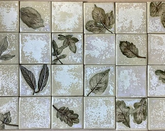 May include: A set of 25 square ceramic tiles with a white background and a distressed look. Each tile features a different pressed leaf design in shades of green.