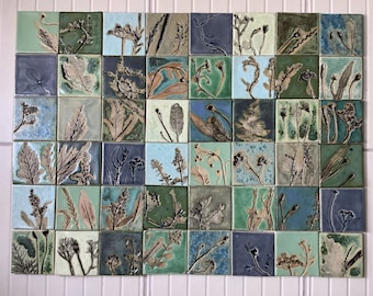 May include: A wall art piece made of 36 square ceramic tiles, each featuring a unique pressed leaf design in shades of green, blue, and brown.