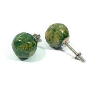 May include: Two green ceramic cabinet knobs with a mottled finish. The knobs have a silver metal screw and washer.