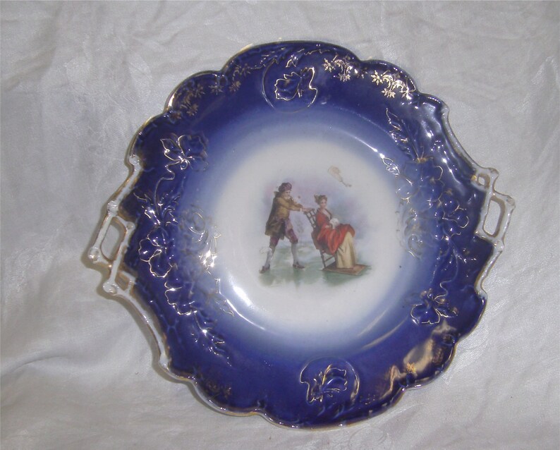 German Poriart Plate \u2013 Man pushing Lady in Snowchair on Lake Flow Blue Edge \u2013 1890/'s