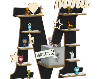 May include: A black letter M-shaped wall shelf with white horizontal platforms featuring small circular cutouts. The shelf is personalised with the name Mina in wood lettering and decorated with various small figurines and a grey Toniebox 2.