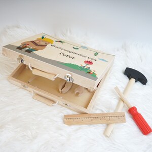 Abmessungen des Werkzeugkoffers, dargestellt mit einem Maßband zur Verdeutlichung der Größe von etwa 29 x 21 x 7 cm.