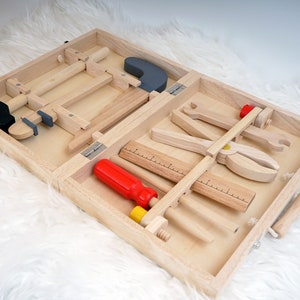 Der Werkzeugkoffer aus Holz aus einer anderen Perspektive, die Tragegriffe aus Kordeln und Holzgriffen sind gut sichtbar.