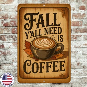 May include: A rectangular metal sign with a wooden effect background. The sign reads "Fall Y'all Need Is Coffee" in brown lettering. A coffee cup with latte art and autumn leaves is in the center. The sign has a distressed look and a "Made in USA" emblem.