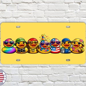 May include: A yellow license plate featuring seven cartoon ducks, each with unique sunglasses and outfits. The ducks are decorated with rainbow, green, red, and blue colors. The license plate has a 'Made in USA' emblem.