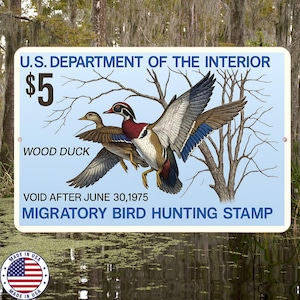 Op de afbeelding: Een rechthoekig bord met een illustratie van een wood duck en de tekst "U.S. DEPARTMENT OF THE INTERIOR" en "MIGRATORY BIRD HUNTING STAMP". Het bord bevat ook de tekst "$5" en "VOID AFTER JUNE 30,1975."