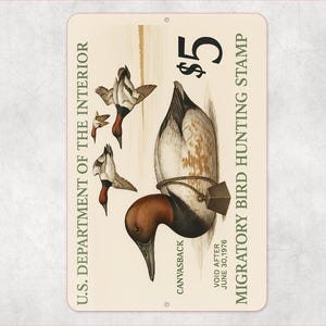 Może przedstawiać: Prostokątny metalowy znak z ilustracją vintage kaczki Canvasback. Znak zawiera tekst "$5 Migratory Bird Hunting Stamp" i "U.S. Department of the Interior". Znak jest kremowy z postarzanym wyglądem.