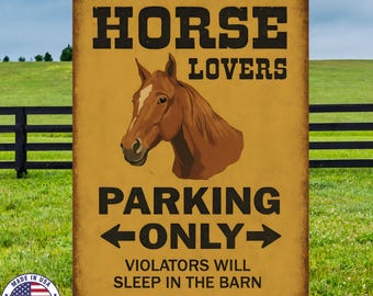 May include: A rectangular metal sign with a distressed finish. The sign reads "HORSE LOVERS PARKING ONLY" with a horse head graphic. The text "VIOLATORS WILL SLEEP IN THE BARN" is at the bottom. A "Made in USA" emblem is in the lower left corner.