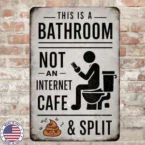 May include: A rectangular metal sign with the text "THIS IS A BATHROOM NOT AN INTERNET CAFE & SPLIT". The sign features a stick figure on a toilet and a smiling poop emoji.