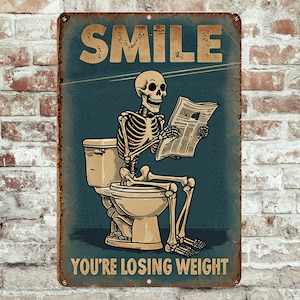May include: A vintage-style metal sign with a humorous illustration. It features a skeleton sitting on a toilet, reading a newspaper, with the words "SMILE" and "YOU'RE LOSING WEIGHT" in bold letters. The sign has a distressed, rusty appearance.