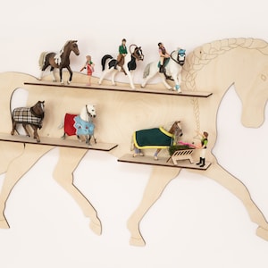 May include: Wooden horse-shaped shelf with two shelves. The shelves are filled with miniature horse figurines and accessories, including a horse with a blanket, a horse with a saddle, and a person riding a horse.