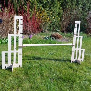 Puede incluir: Un circuito de obst&aacute;culos de madera para mascotas peque&ntilde;as, con dos torres conectadas por una barra horizontal. Las torres est&aacute;n hechas de madera contrachapada y tienen una serie de recortes que se asemejan a ventanas.