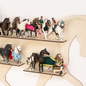 May include: A wooden horse shelf with two shelves, featuring a variety of miniature horse figurines and riders. The shelf is painted in a light wood color and has a simple design.