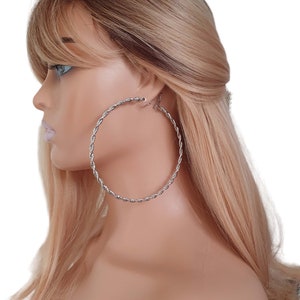 May include: Silver hoop earrings with a twisted rope design. The earrings are large and circular.