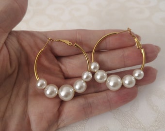 May include: Gold hoop earrings with a row of white faux pearls.
